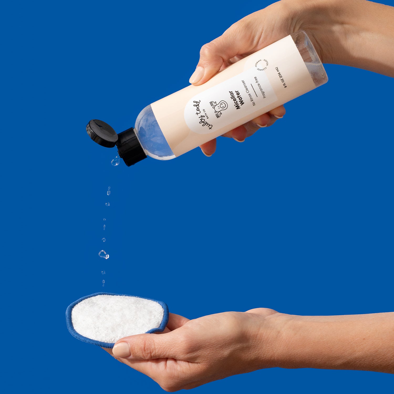 Hands holding the Fragrance Free Micellar Water and Pouring it on the cotton pad.